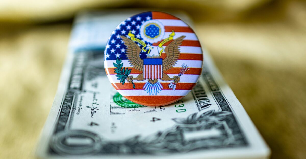 An american flag pin sitting on top of a one dollar bill