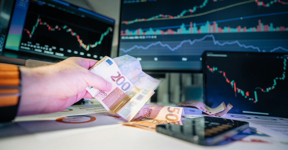 A person holding money in front of a computer screen