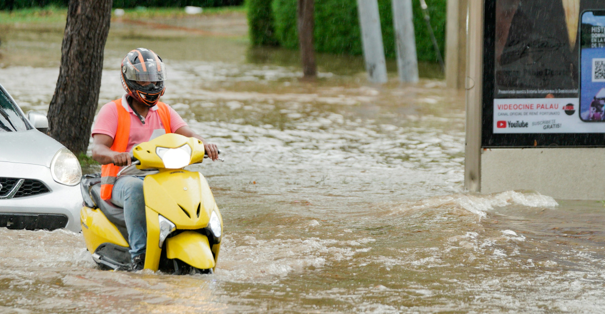A couple of people on a motor scooter in a flooded street