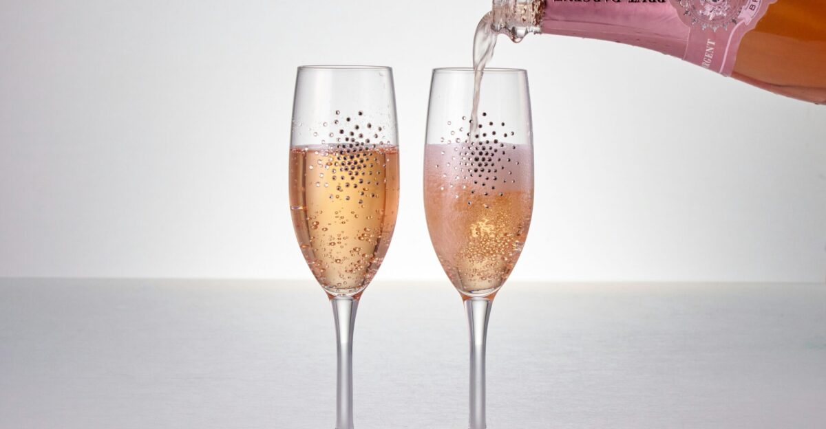 A bottle of champagne being poured into two wine glasses