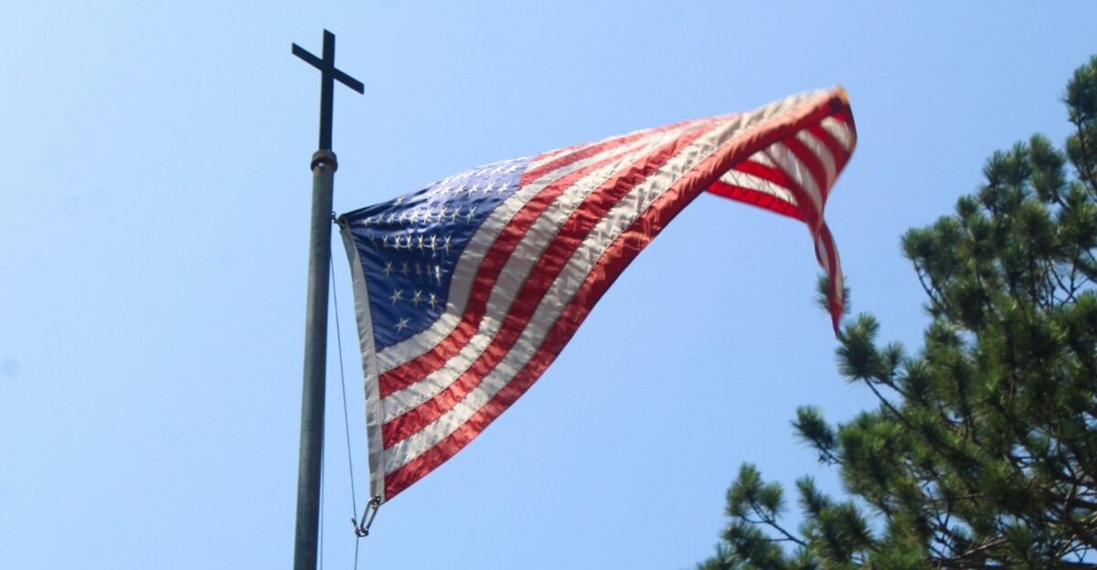 An american flag flying in the wind on a pole