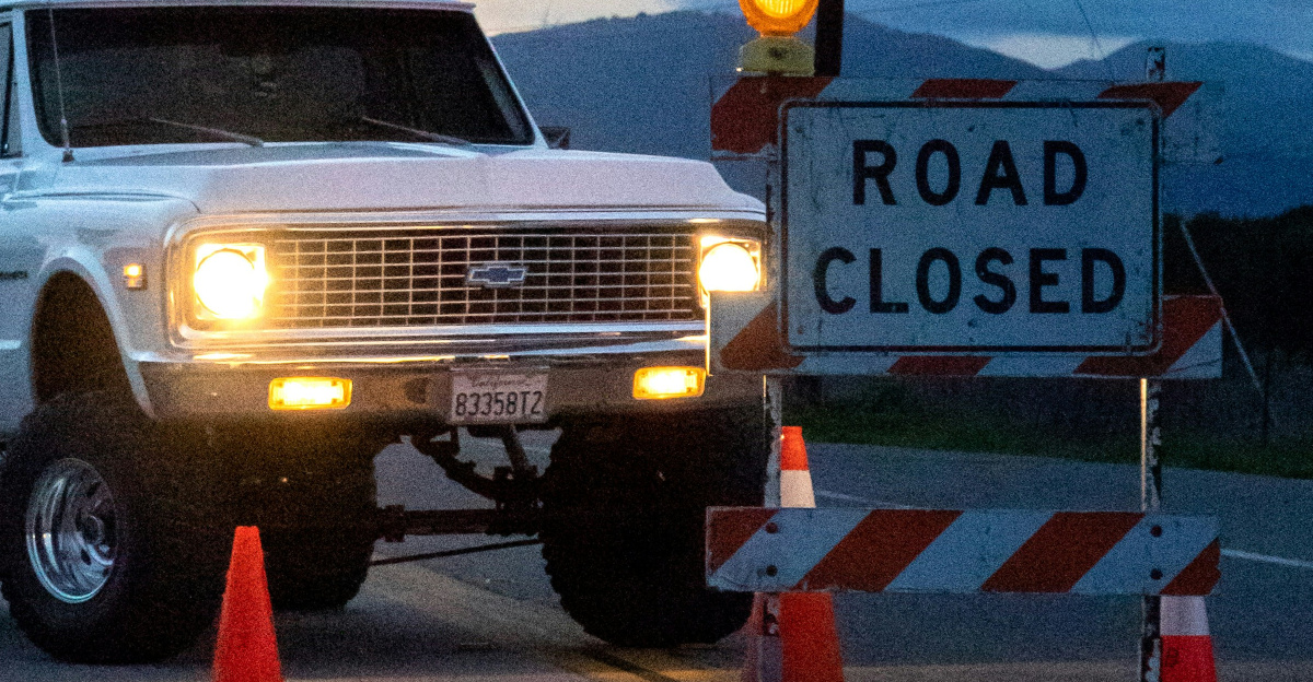 A white truck driving down a street next to traffic cones