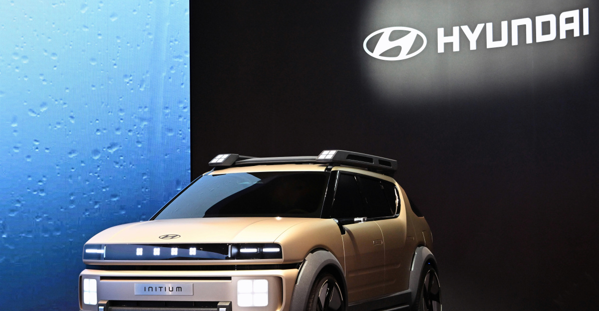 A small suv is on display in front of a sign