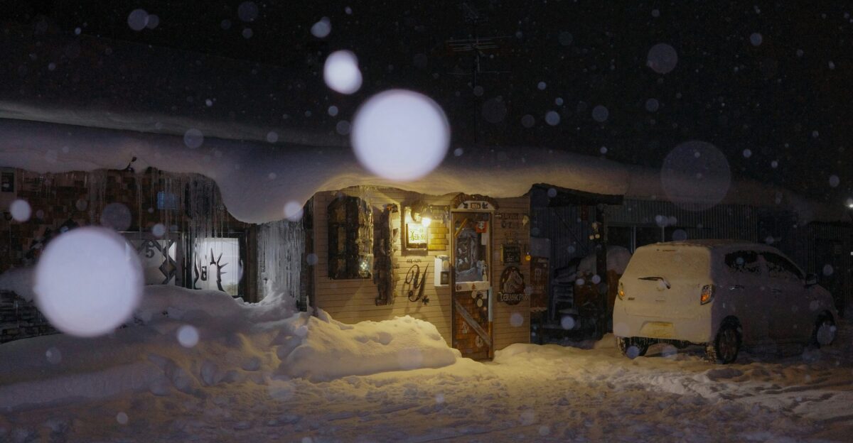 A truck parked in front of a house covered in snow