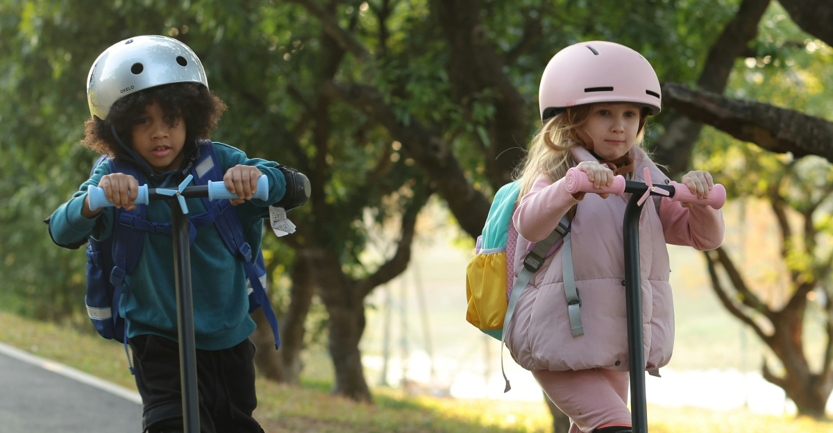 Two young children riding scooters down a road