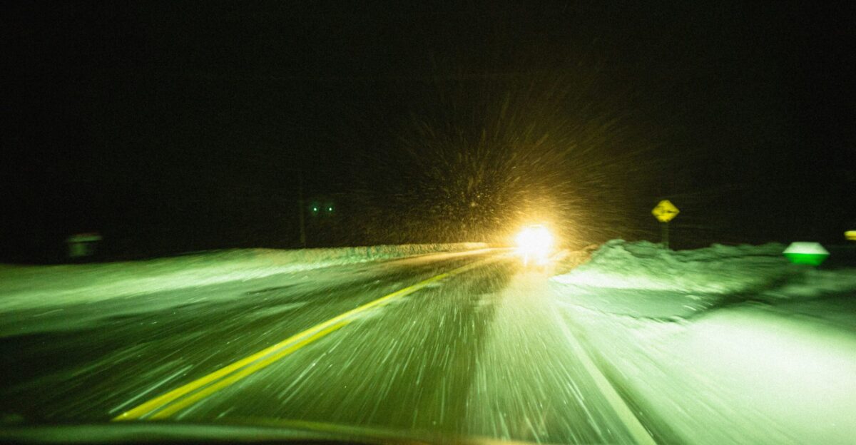 A car driving down a snowy road at night