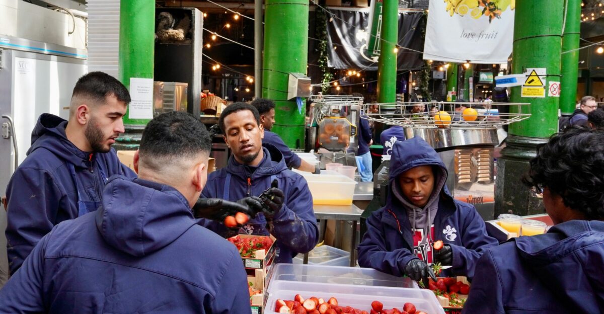 People are preparing fruit at a market stall