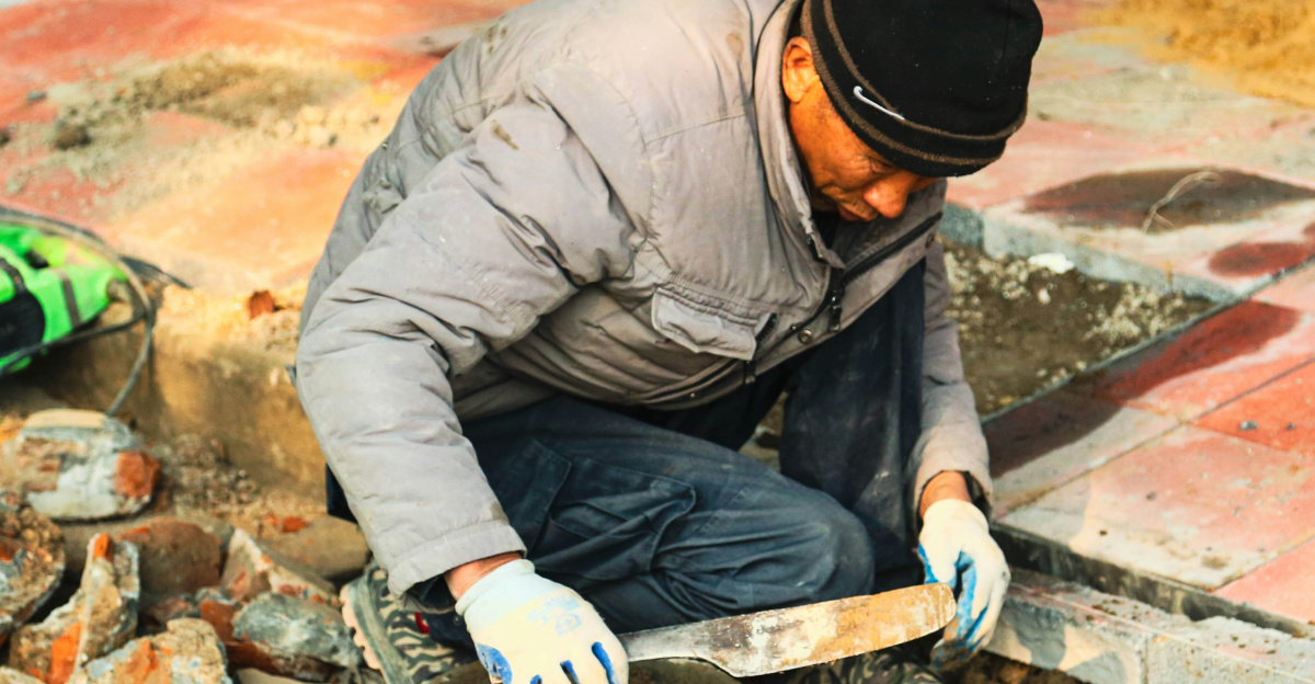 A construction worker is working on the pavement.