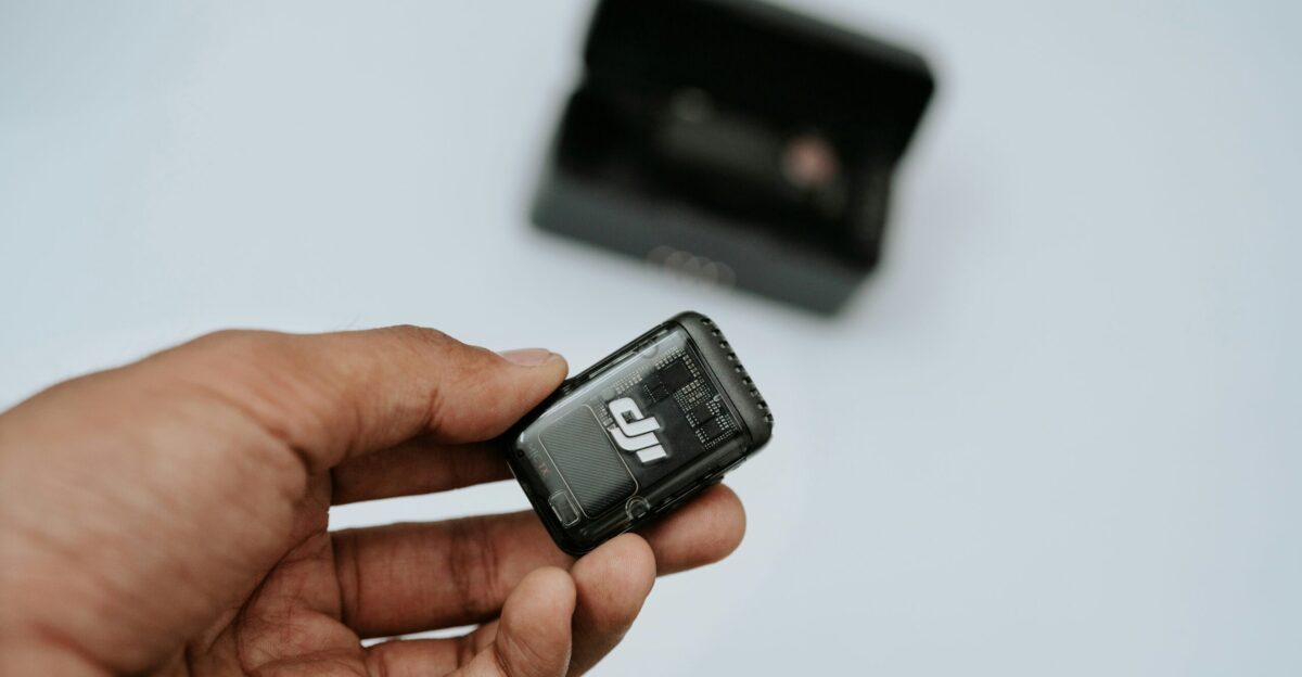 A hand is holding a black dji device