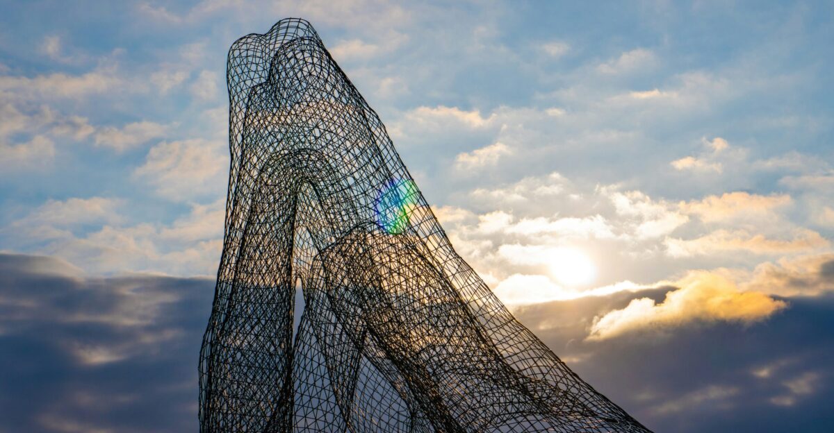 Abstract sculpture stands against a cloudy sky