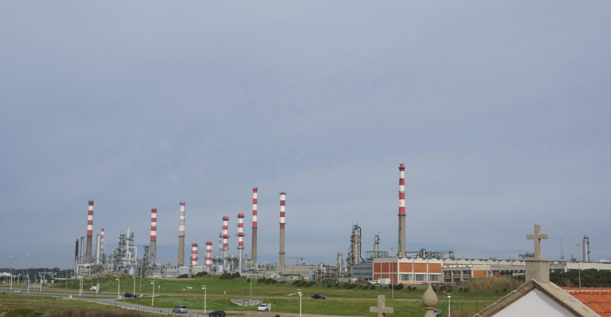 Oil refinery chimneys stand under a cloudy sky