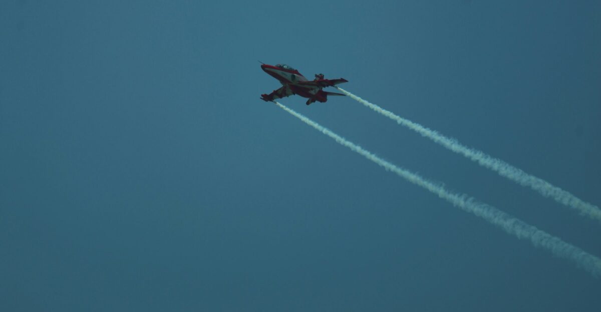 A fighter jet flies through a bright blue sky