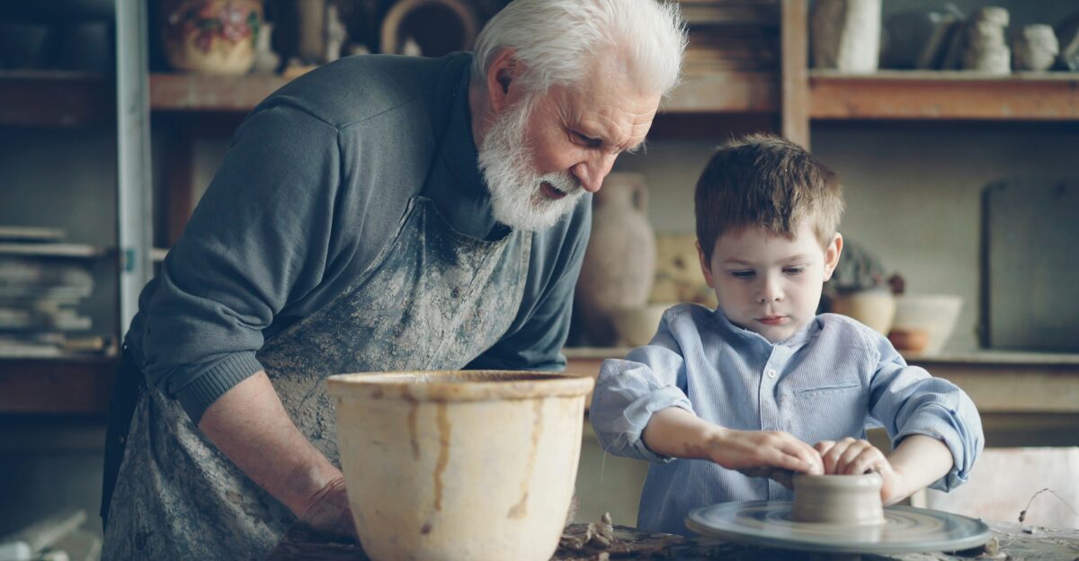 Grandfather teaches grandson pottery
