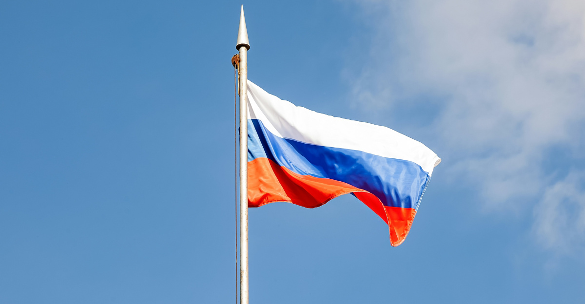 The russian flag waves against a clear, blue sky.