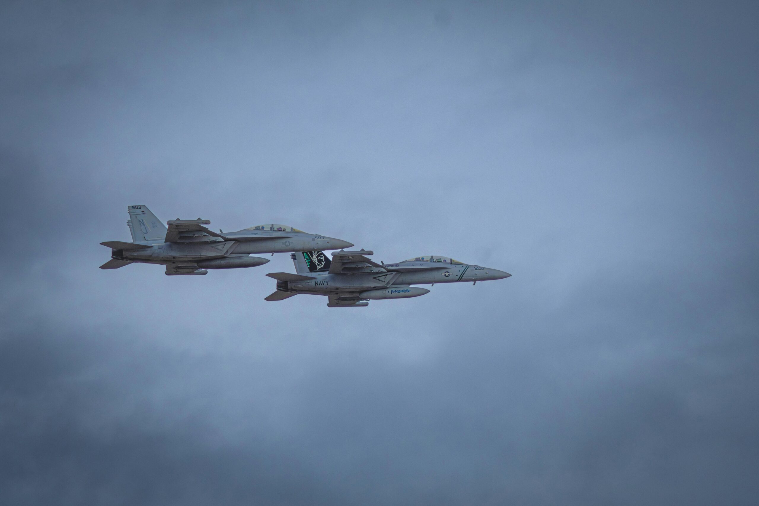 Two fighter jets flying in a cloudy sky