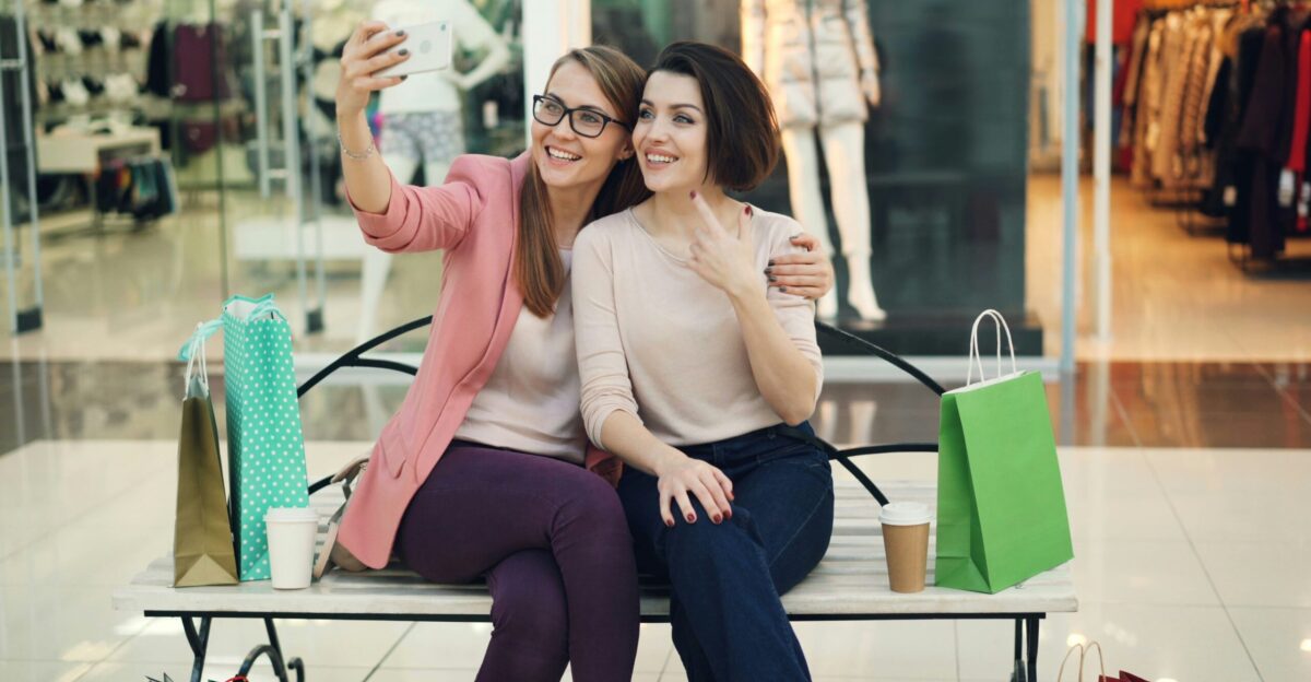 Two smiling women taking a selfie in a shopping mall