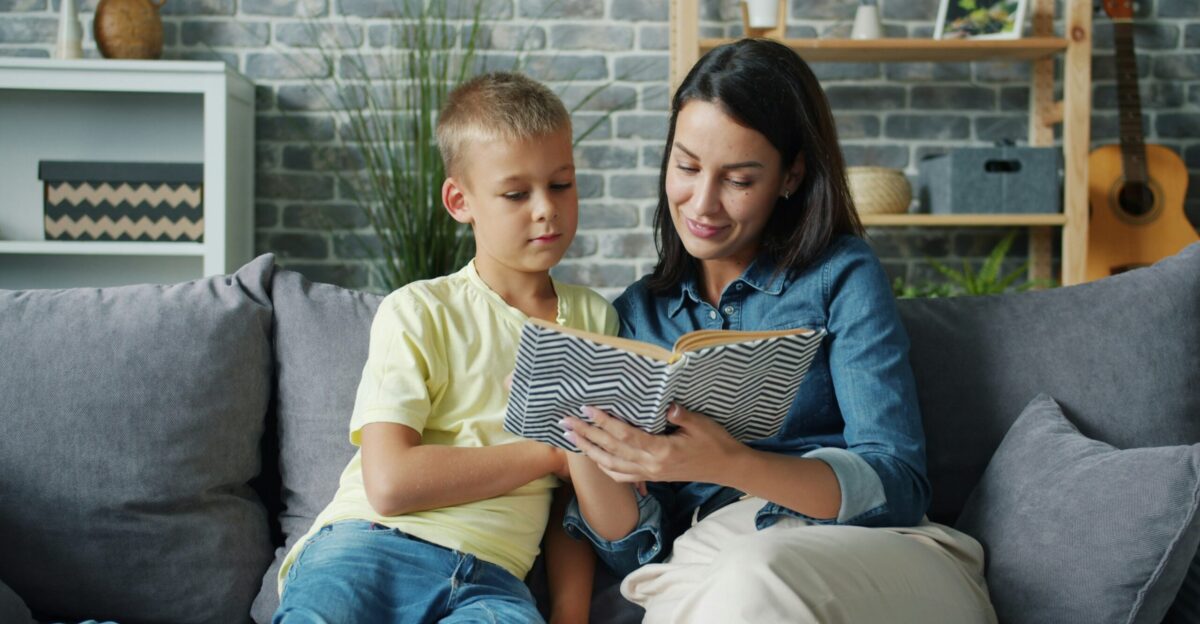 Mother and son reading a book together on sofa