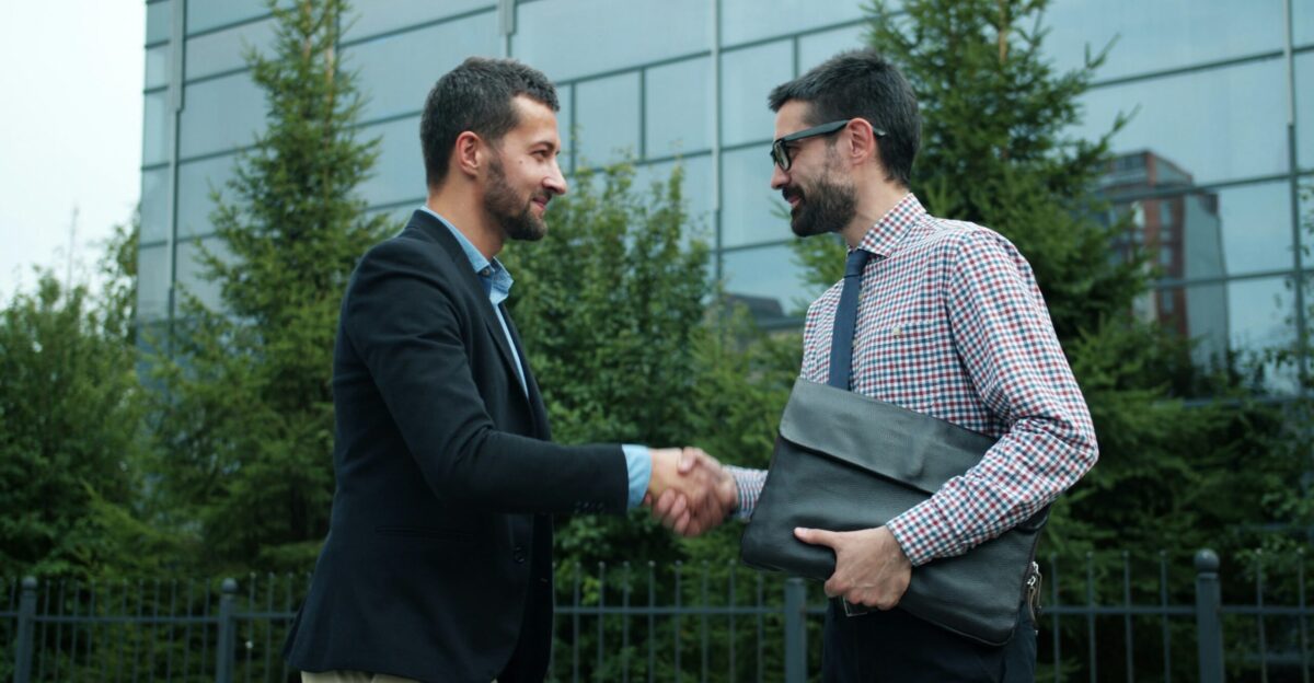 Two businessmen shaking hands outside modern building