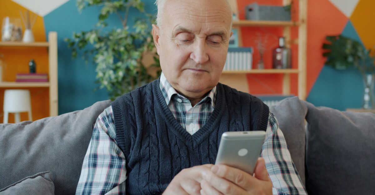 Elderly man using a smartphone on a couch