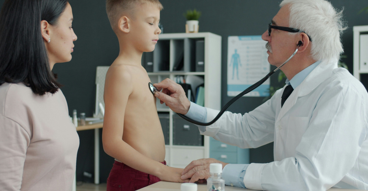 Doctor examines boy's chest with stethoscope while mother watches.