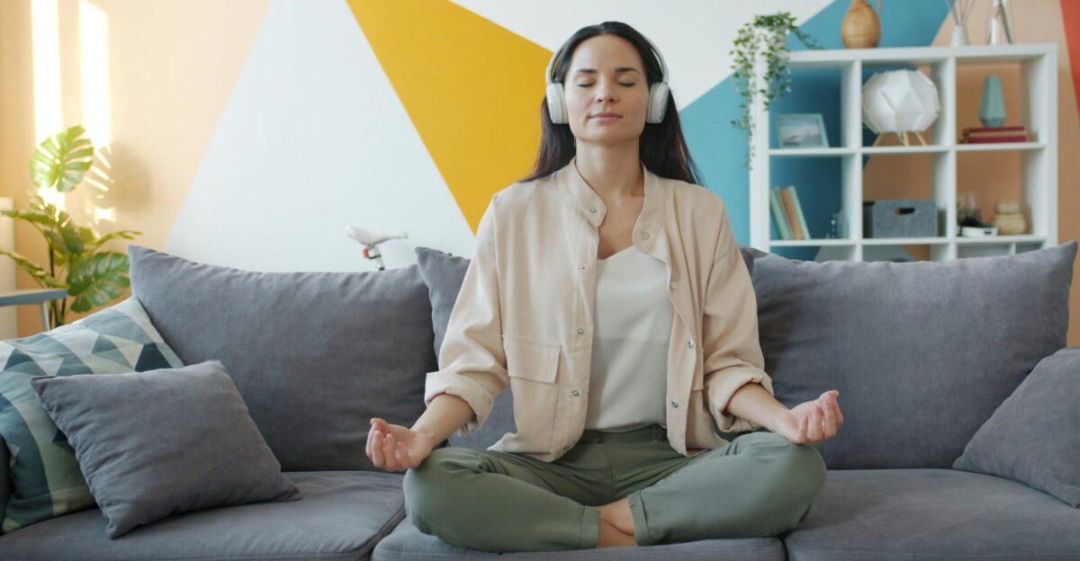 Woman meditating on couch with headphones on
