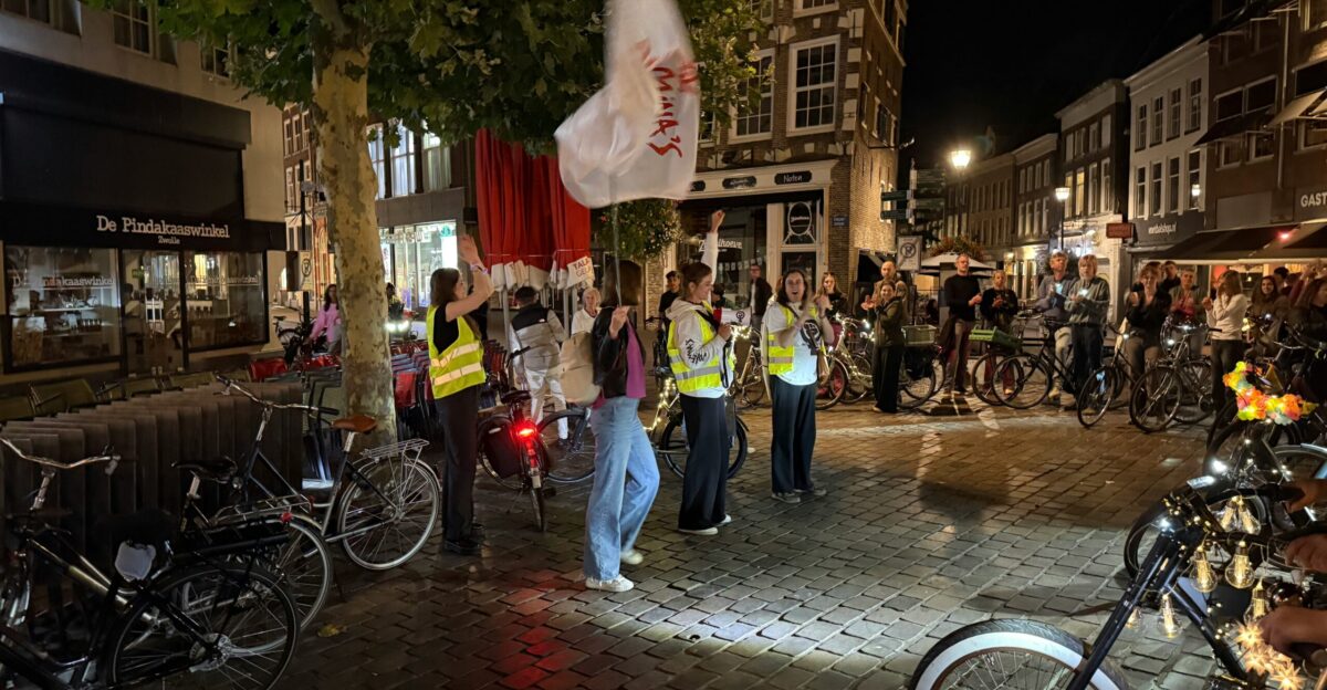 People with flags gather at night in a city square