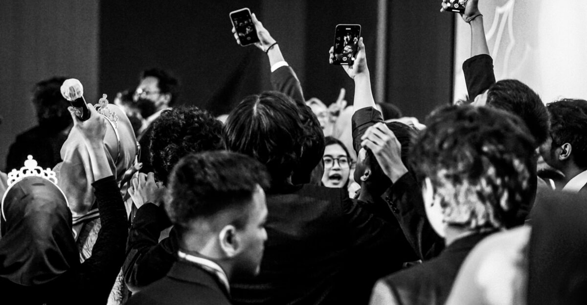 Crowd of people holding up phones recording event