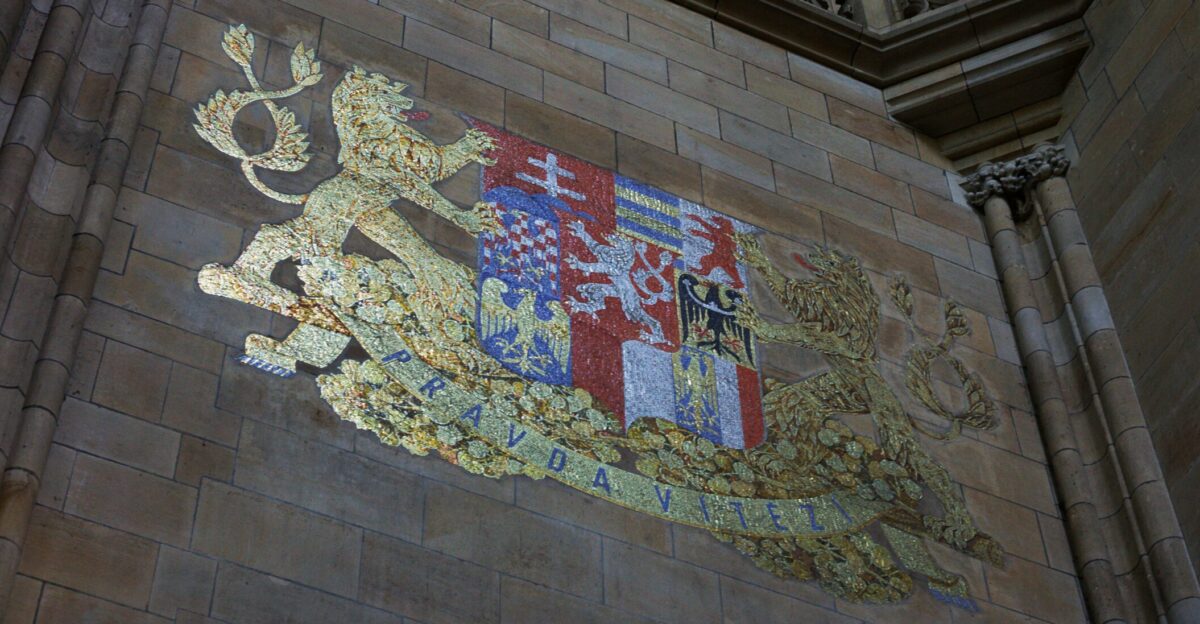 Ornate crest with lion and colorful shield on stone wall