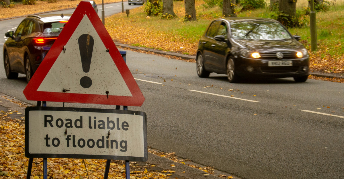 Road liable to flooding sign with cars and bus.