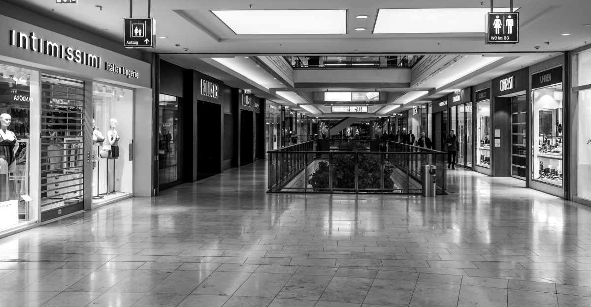 Empty shopping mall corridor with storefronts on sides.