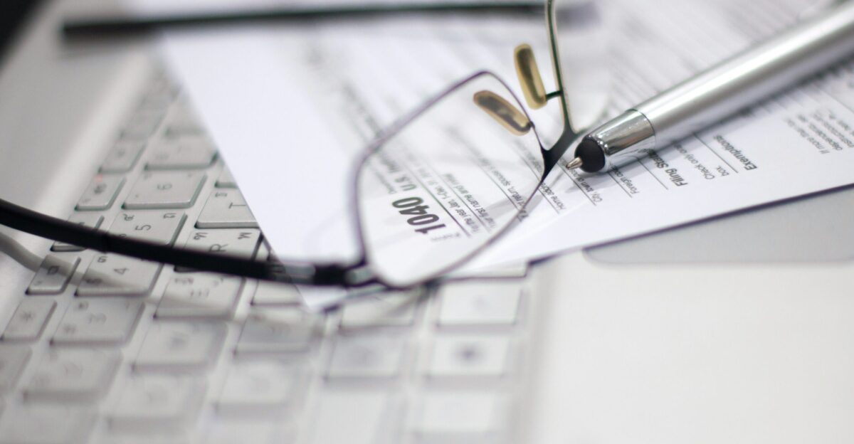 Glasses and pen on tax form and laptop