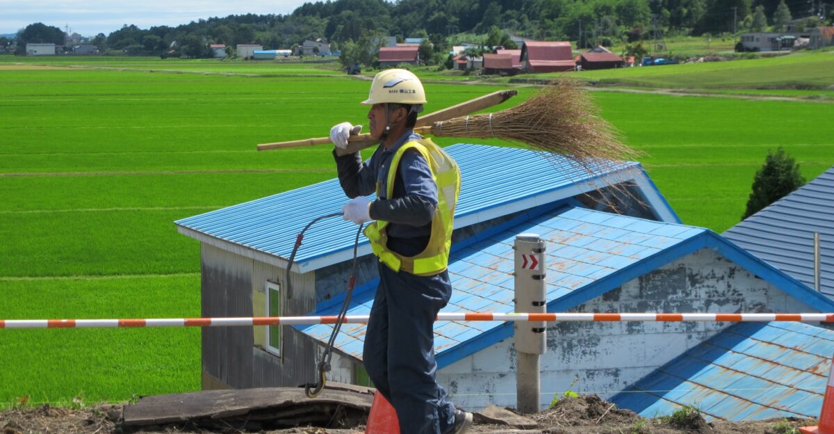 A road worker carries his gear over a bridge in rural Hokkaido Japan
