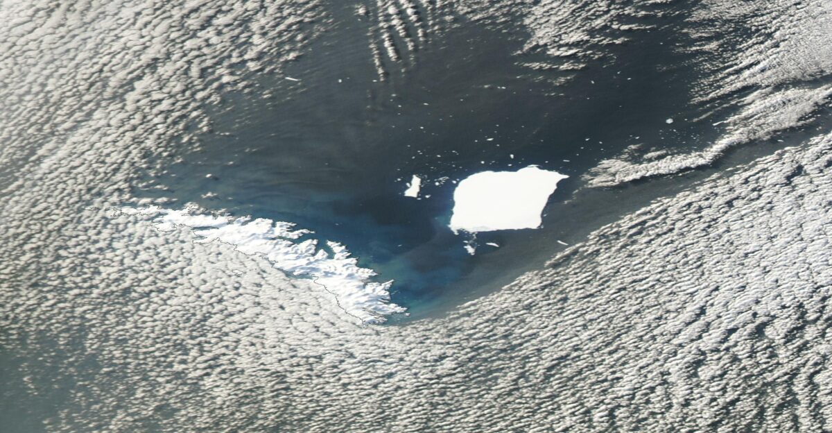 Clouds briefly parted over the Southern Ocean to allow a clear-sky peak at Iceberg A23A on August 19 2025 The Moderate Resolution Imaging Spectroradiometer MODIS on NASA s Aqua satellite captured this true-color image of the big berg and its fragments on that same day At that time A23A was continuing to slowly crumble as it floated roughly 100 miles 160 km north of South Georgia Island Thousands of iceberg pieces litter the ocean surface near the main berg creating a scene reminiscent of a dark starry night Though these fragments appear small in the image many measure at least a kilometer across and would pose a risk to ships Several fragments floating in the general area of A23A remain large enough to be monitored by the US National Ice Center USNIC including A23D A23E and A23F Another fragment A23C broke from A23A in mid-April 2025 but has melted or broken up and is now too small to be monitored The largest fragment A23F was calved from A23A on August 17 Satellite imagery on August 21 suggests that A23F had already broken into two pieces