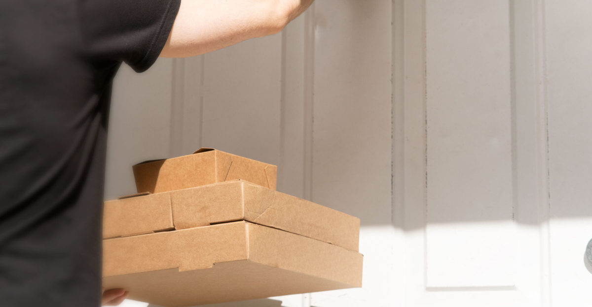 An image of a delivery driver knocking on a white front door to deliver three cardboard takeaway boxes. 
This image is free to use under the Creative Commons Attribution Licence. Feel free to use it wherever you need to! If you do, please link back to us at meanwell-packaging.co.uk/