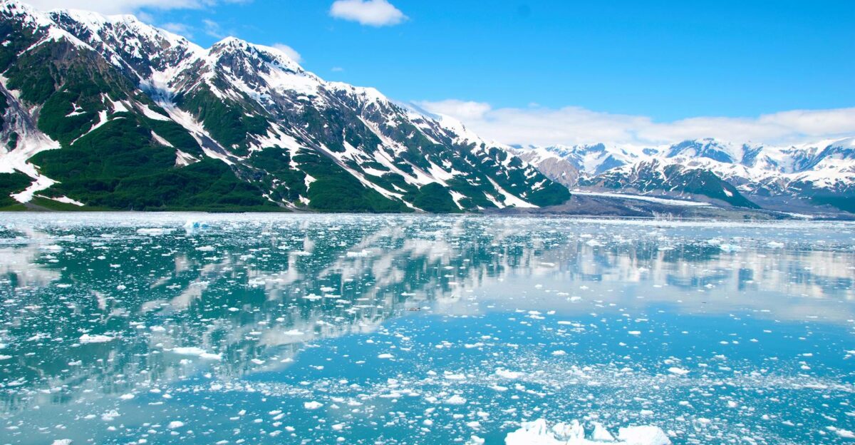 A breathtaking view of Alaskan glaciers reflecting on tranquil icy waters under a clear blue sky