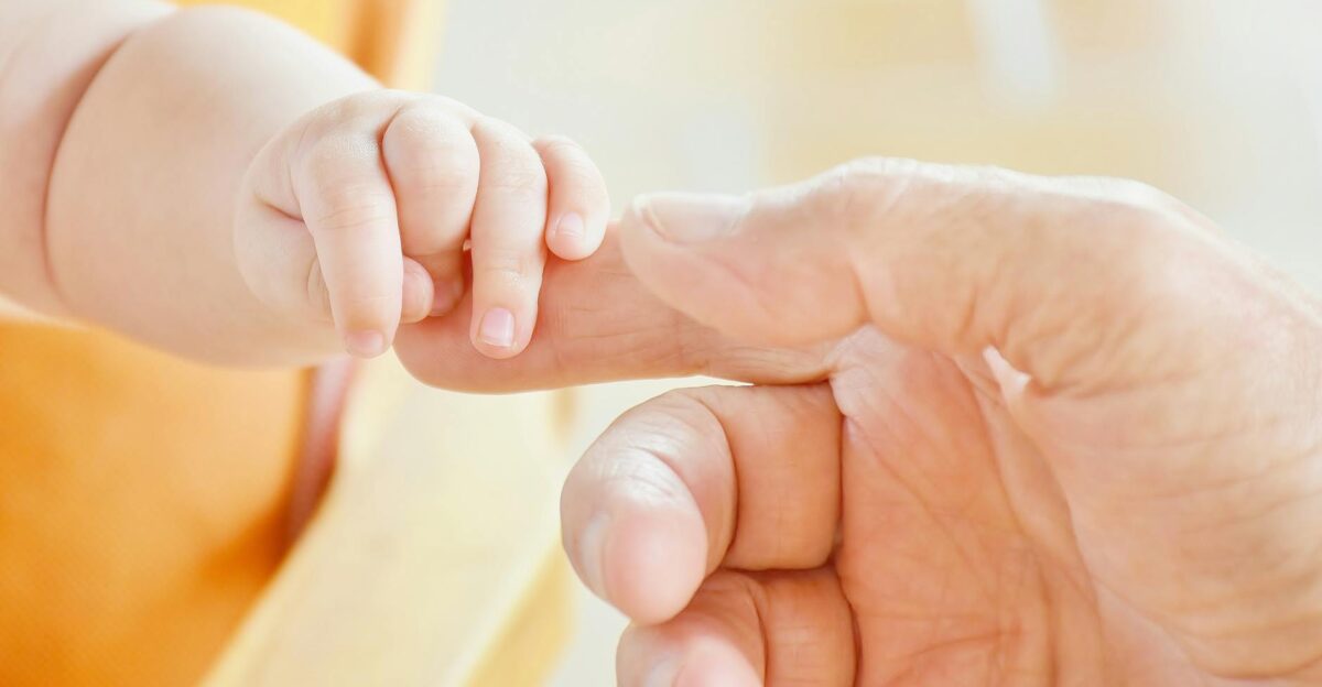 Close-up of a baby s hand holding an adult s finger symbolizing parental love