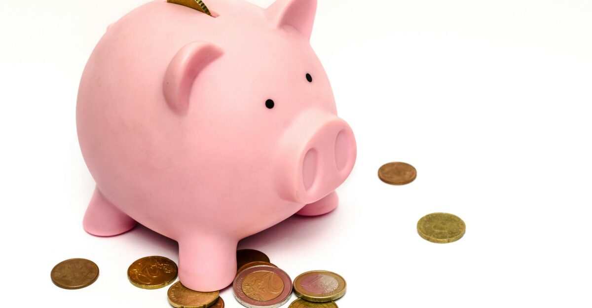 A pink piggy bank surrounded by scattered coins symbolizing savings and financial investment