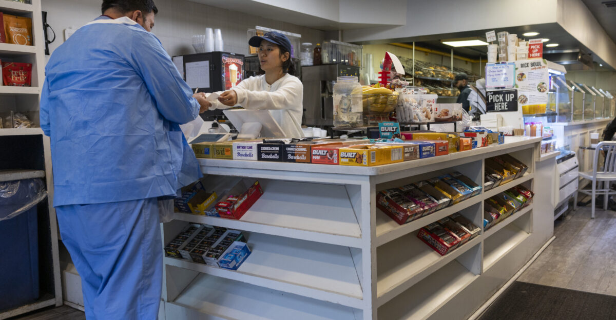 A cashier hands a receipt to a customer at the counter of a bagel shop in New York City