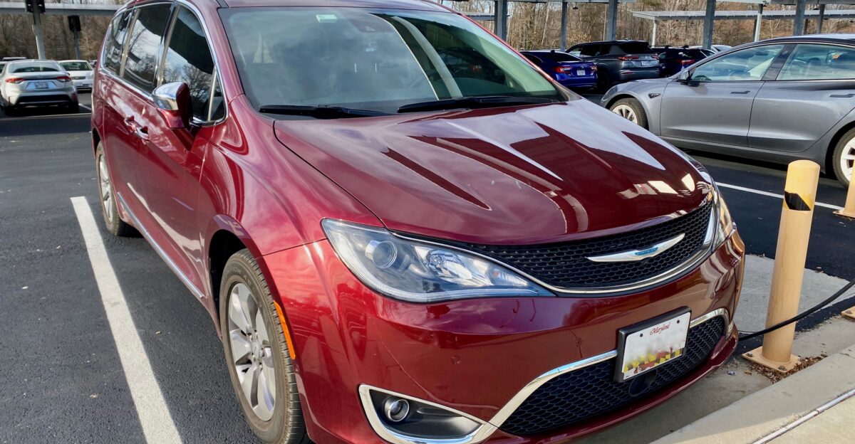 Chrysler Pacifica Hybrid minivan finished in Velvet Red pearl-coat Photographed while fueling at a charging station that is solar panel powered
