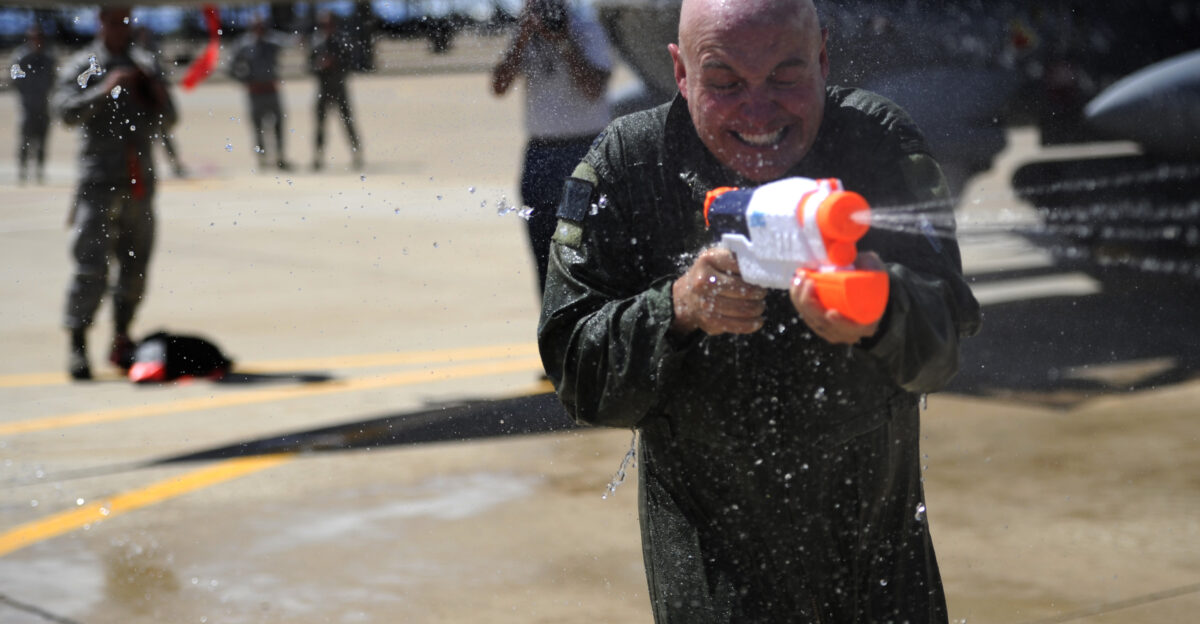 U S Air Force Col Scott Long commander 388th Fighter Wing sprays his wife Staci Long with a water gun on his final flight as an Air Force airman at Hill Air Force Base Utah June 6 2013 On the final flight of an Air Force career it is tradition to have a water gun battle upon the pilots exiting of their plane U S Air Force photo Senior Airman Allen Stokes