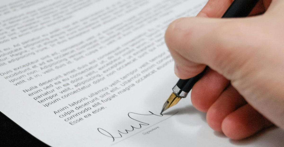 Close-up of a hand signing a legal document with a fountain pen, symbolizing signature and agreement.
