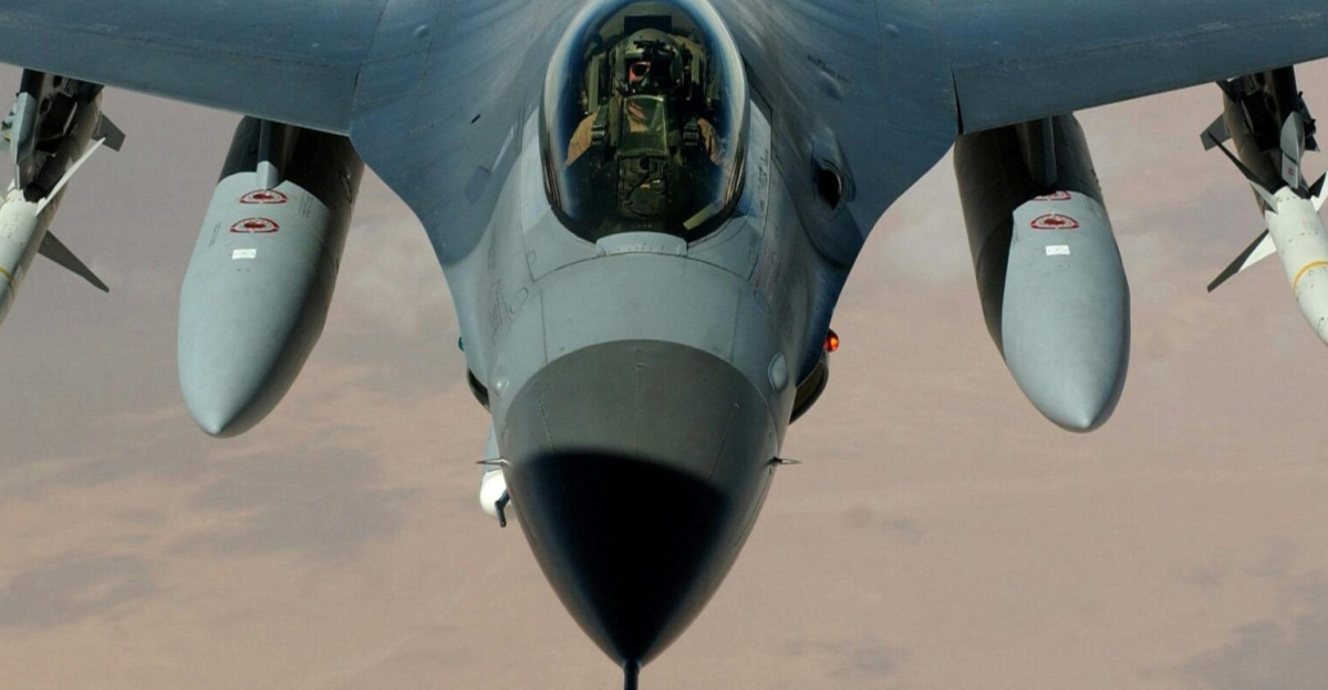 Powerful fighter jet soaring through clouds with visible missiles.