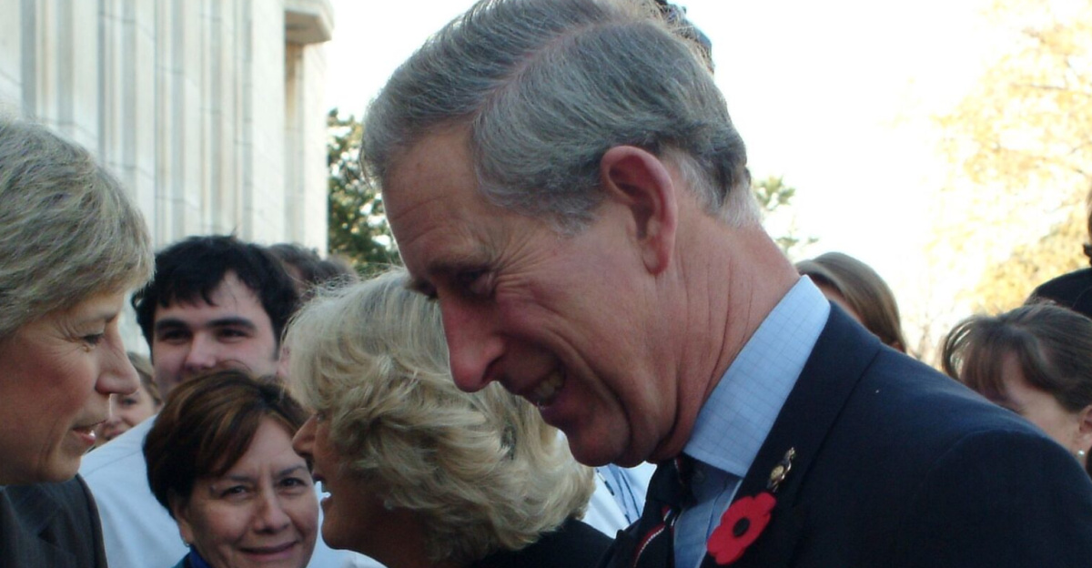 Group of figures outdoors; in the foreground, Karen Hastie Williams and Charles, Prince of Wales, shake hands.