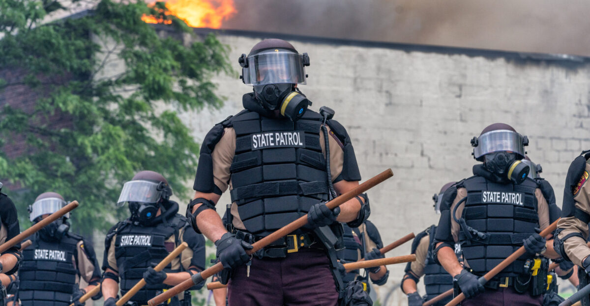 Minnesota State Patrol troopers stand in formation wearing riot gear and holding wooden batons at Minnehaha Avenue and 27th Avenue South near the Minneapolis Police Department s 3rd Precinct as the Minneapolis Fire Department battles blazes at Lake Street businesses following the publication of a video showing a white Minneapolis police officer kneeling on the neck of George Floyd a handcuffed and unarmed Black man killing him