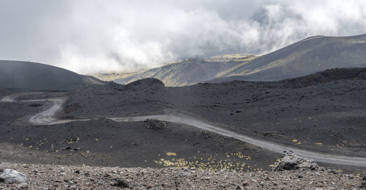 A road at Mount Etna in Sicily Italy The Etna gondola lift is seen in the far background