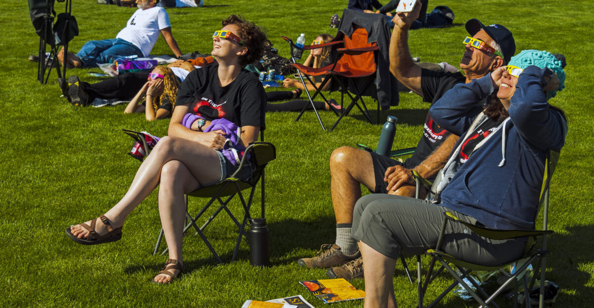 People watching the early phase of the August 21 2017 solar eclipse at Riverside Park in Rexburg ID USA through their eclipse glasses
