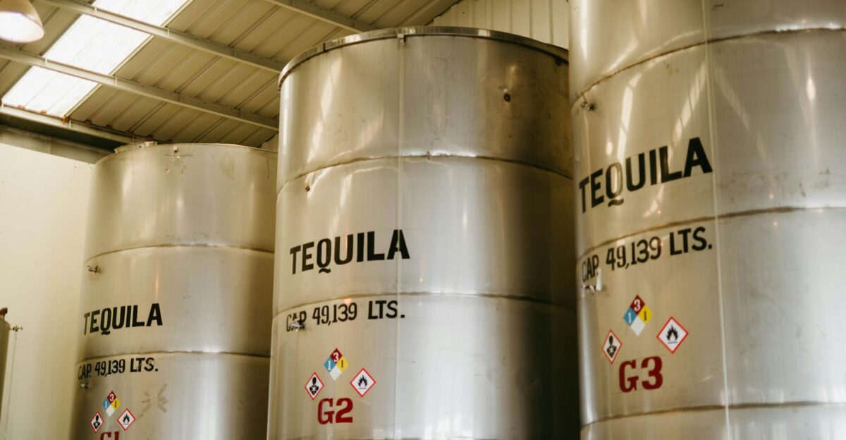 Large tequila storage tanks inside a Mexican distillery with visible capacity markings