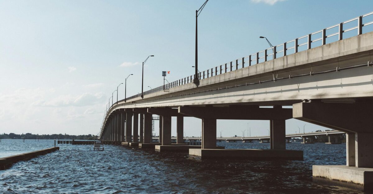 Wide-angle view of a concrete bridge over a river under a clear blue sky showcasing modern infrastructure