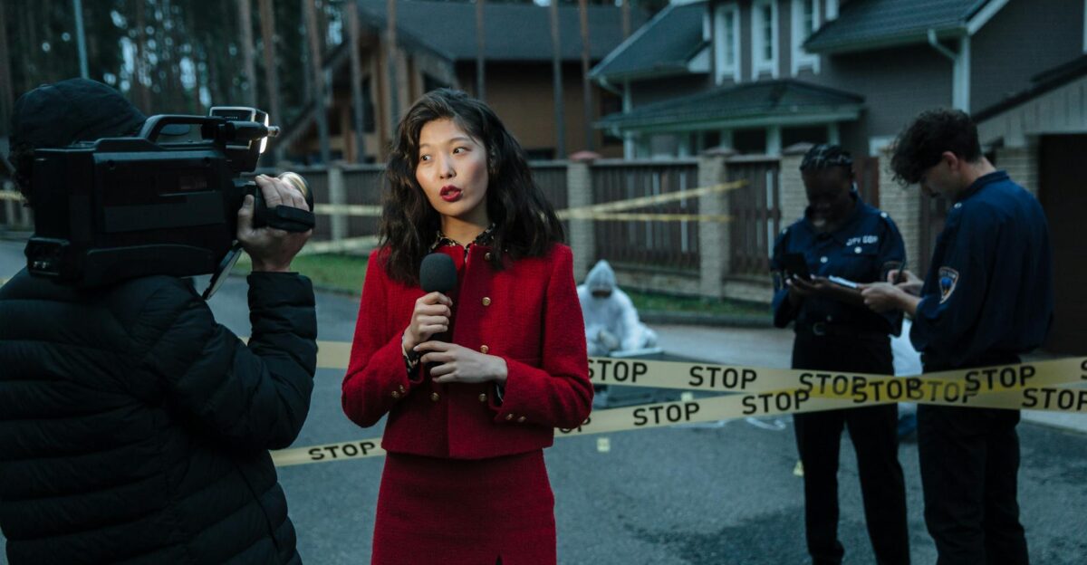 A journalist reporting from a crime scene with police officers and cameraman