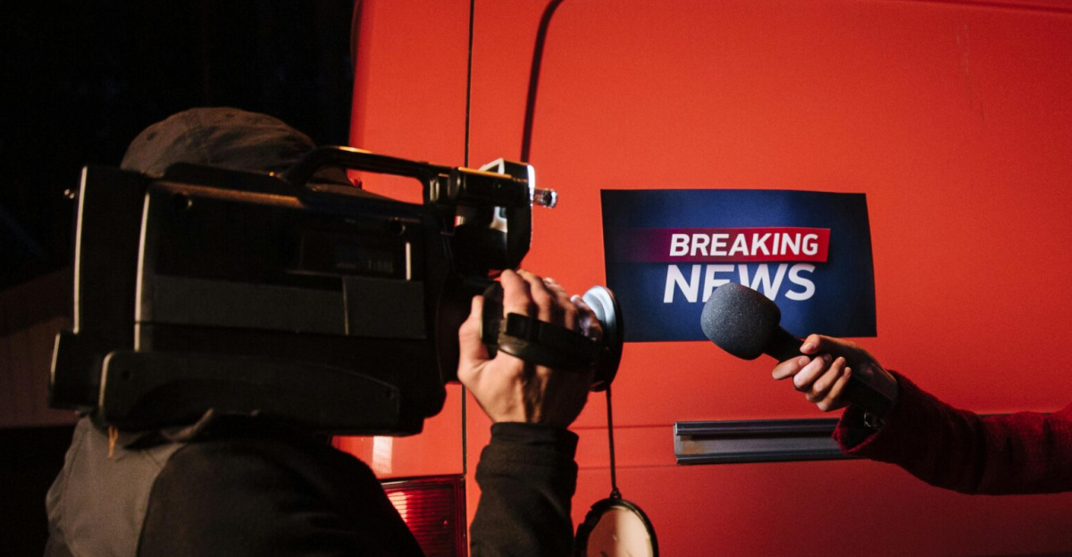 Asian female reporter with cameraman conducting a nighttime news broadcast beside a news van.